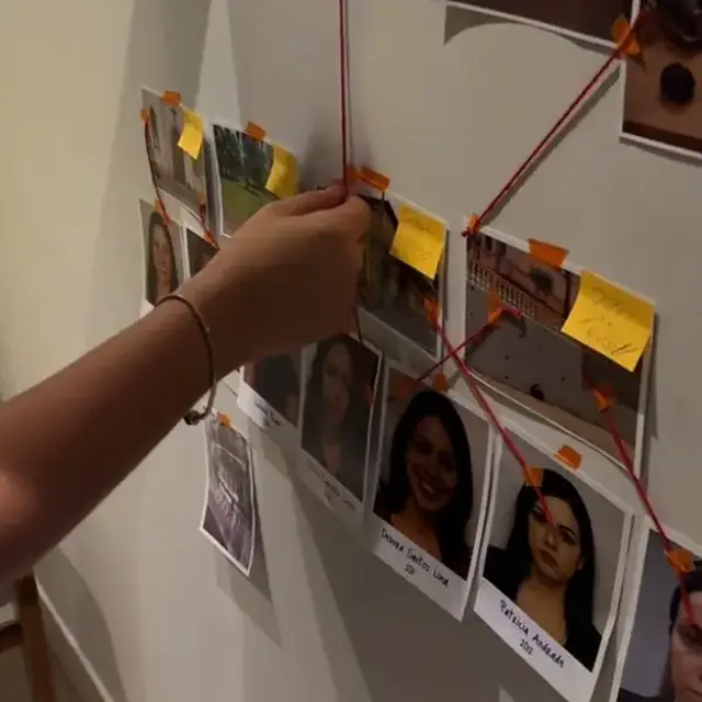Muro de investigación con fotos de sospechosos conectadas con hilo rojo